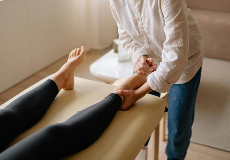 A therapist provides a leg massage to a woman in a calm, serene indoor environment.